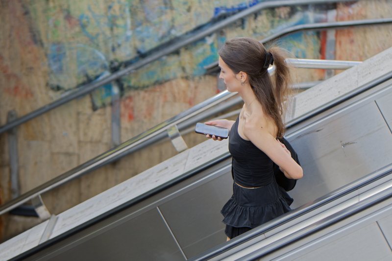 12 - Girl descending an escalator while looking at a smartphone